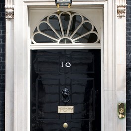The black front door of 10 Downing Street, with its white number 10, a lion's-head knocker and a fanlight above.