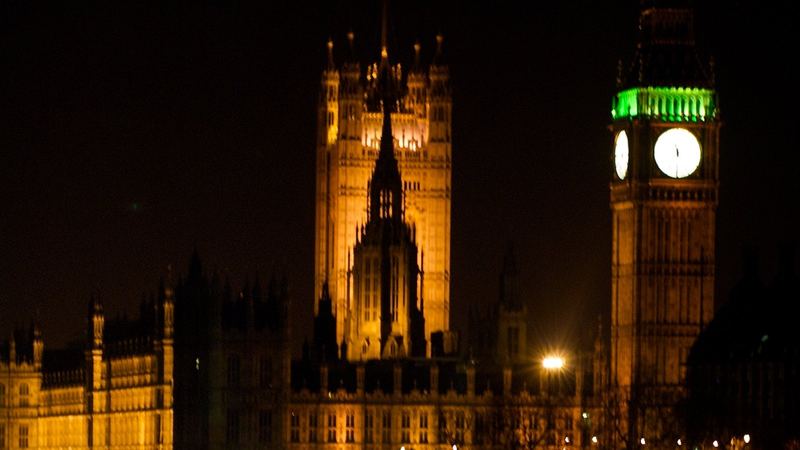 The Palace of Westminster floodlit at night, with the clock tower lit against a dark sky.
