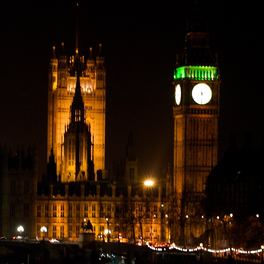 The Palace of Westminster floodlit at night, with the clock tower lit against a dark sky.